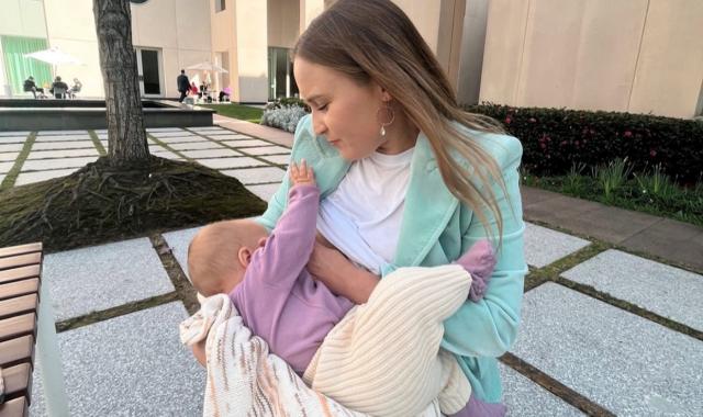Holly Rankin sitting outside Parliament House in the courtyard breastfeeding her daughter Maggie