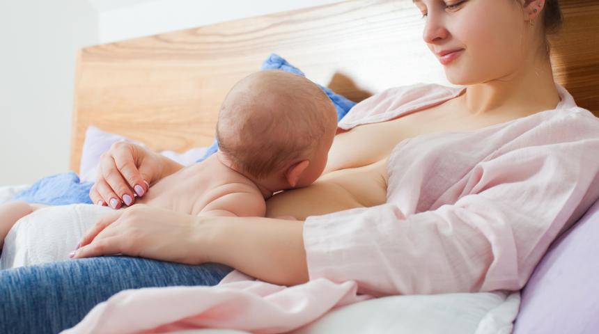 Baby lying on mother feeding