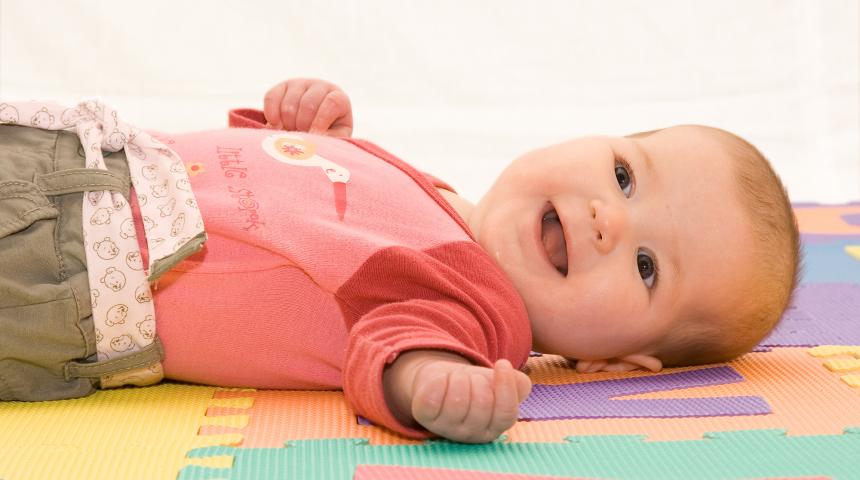 Baby lies on floor and smiles