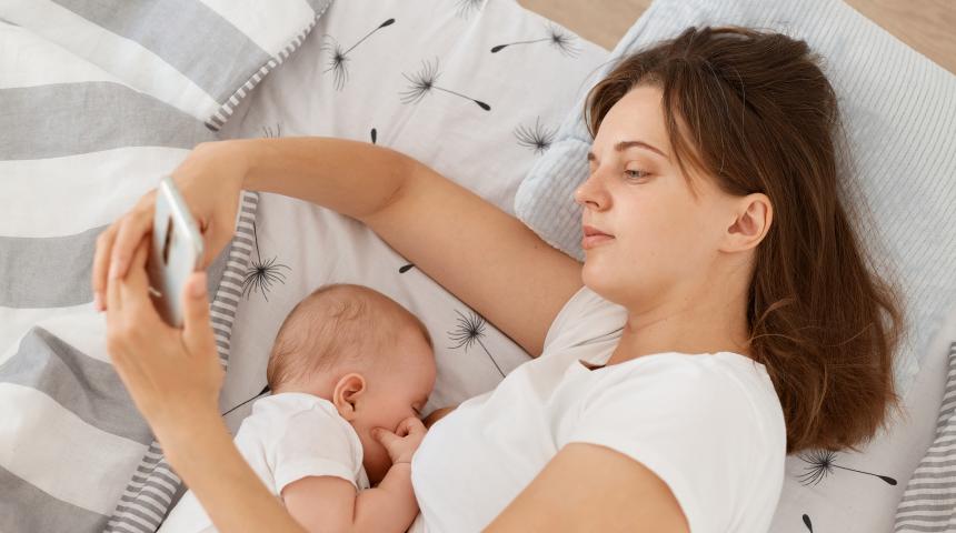 mum feeding baby and looking on phone