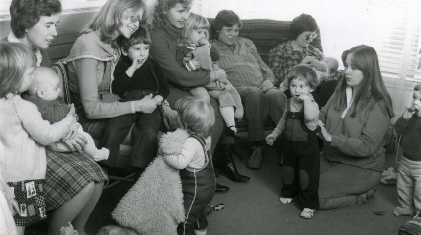 A black and white image of a group of mothers, babies and young children in a past era.