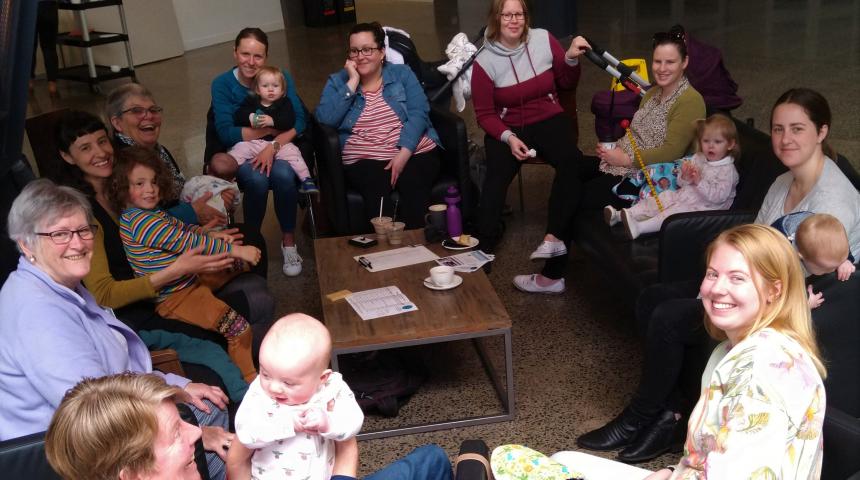 Group of women, babies and children sitting around the table.