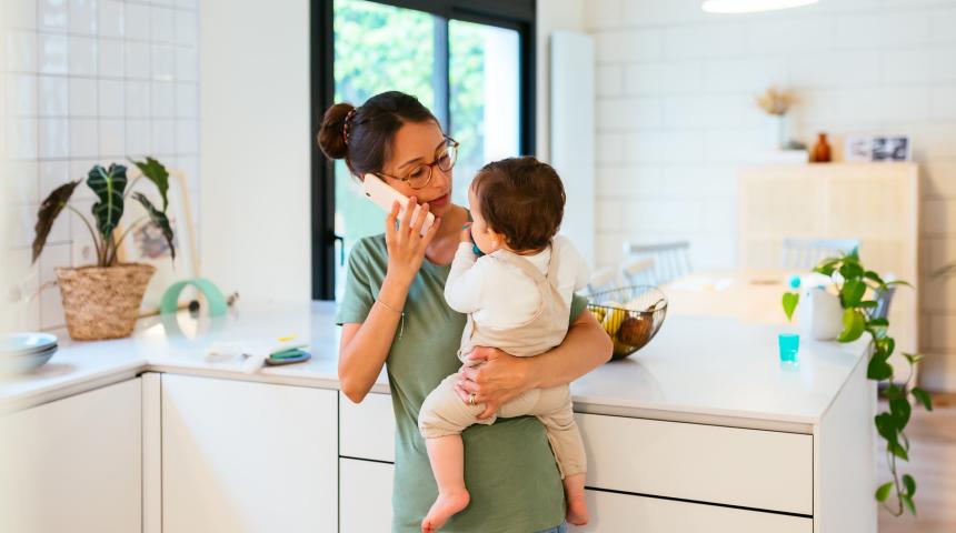 Mum on phone to Helpline with baby in arms