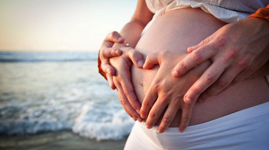 Pregnant women holding belly with partners hands