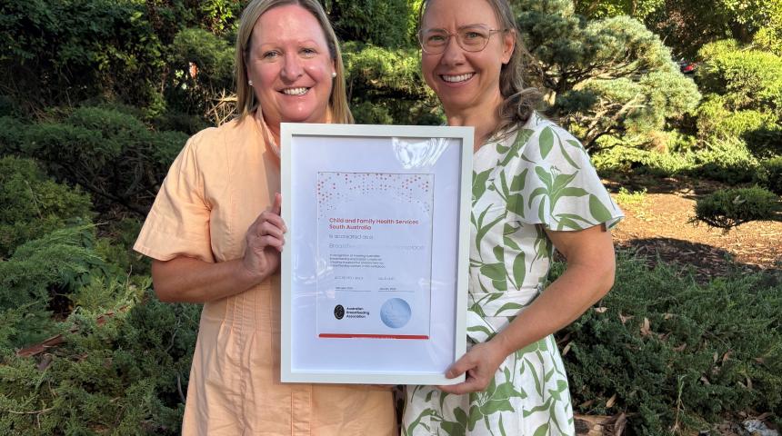 Two employees holding a framed BFW Certificate