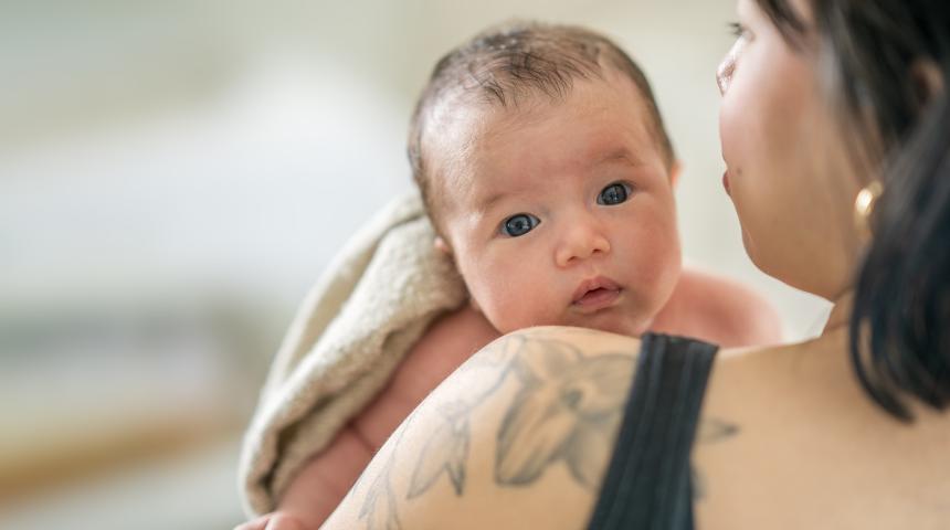 A baby looks over their mother's shoulder