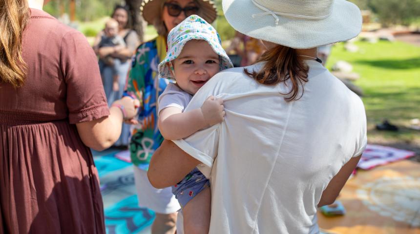 Mother holding her infant at an outdoor gathering