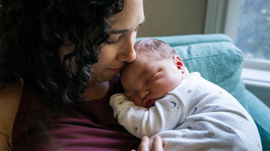 A mother holds her sleeping newborn baby