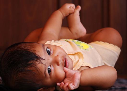 Baby lies on the floor and smiles