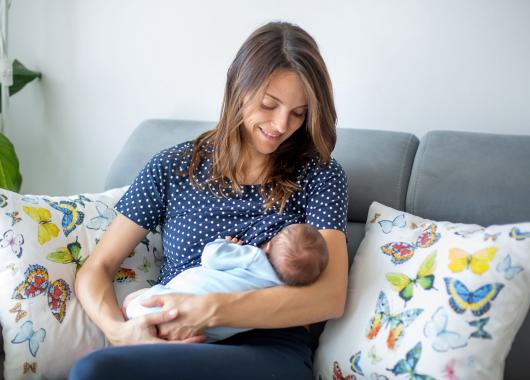 Mum sitting on couch breastfeeding