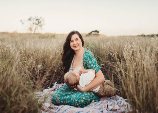 Mother and toddler breastfeed outdoors