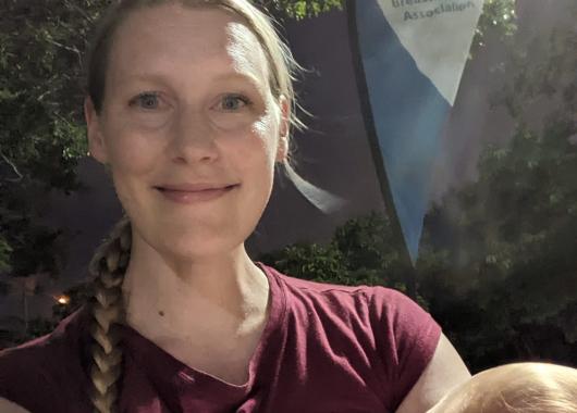 mother breastfeeding with ABA teardrop banner in background