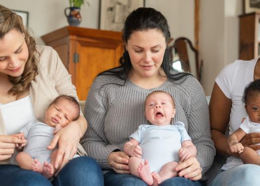 three mothers sitting together holding their babies on their lap