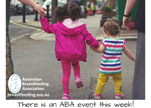 Two children are crossing a road holding hands. They are walking away from the camera. One is skipping, presumably happy to be going to an ABA event