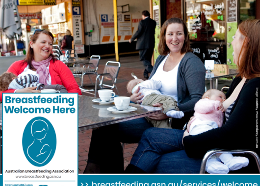 Three women enjoy hot drinks at a cafe table.All three are breastfeeding and smiling at each other. An image in the corner says "Breastfeeding Welcome Here"