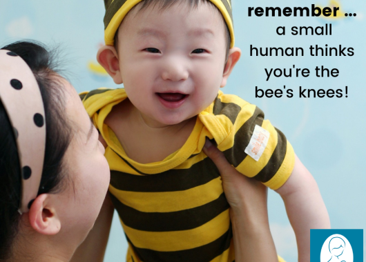A baby dressed in yellow and black striped bodysuit and beanie is being held up by a woman with a polka-dot headband. The text says "On hard days: remember ... a small human thinks you're the bee's knees" 