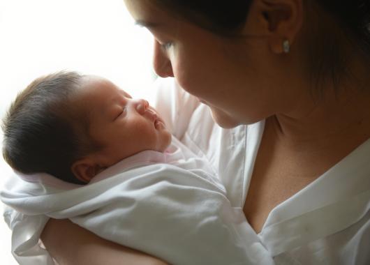 A woman holds her sleeping newborn baby