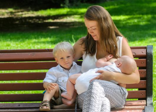 Mother breastfeeding in park with child