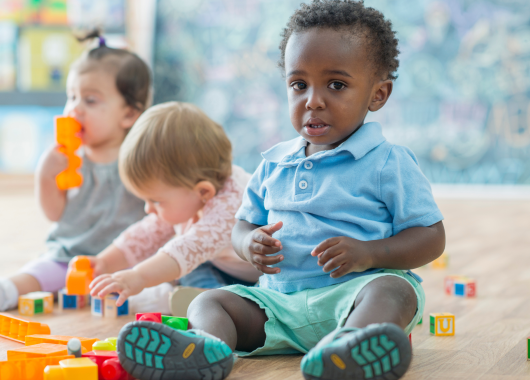Image of three infant sitting playing with toys