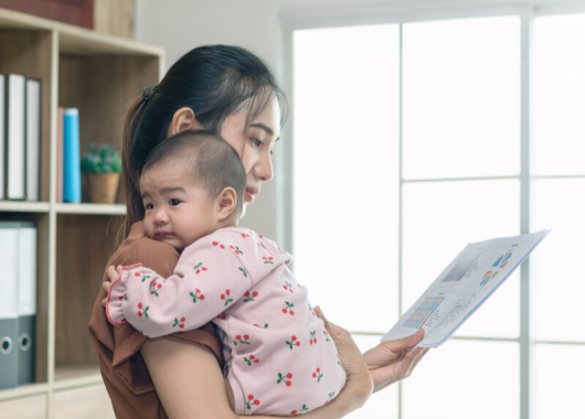 A woman is at work and holding her baby.