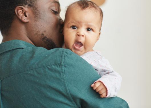 father holding yawning baby