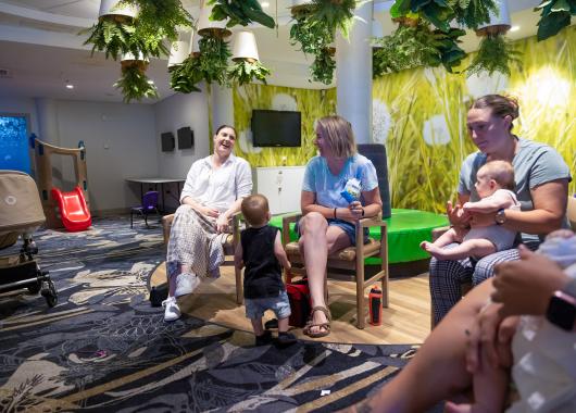 A group of mothers and babies sitting in a circle chatting.