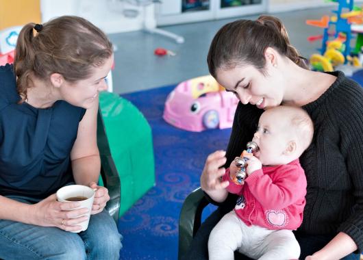 Two women talking with child on lap