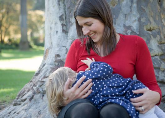 Mother breastfeeding a toddler in a park