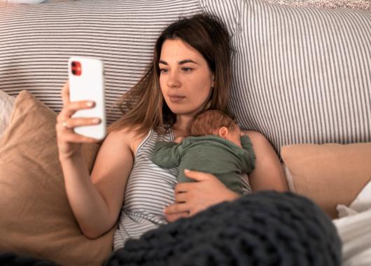 Mother with newborn looking at a mobile phone