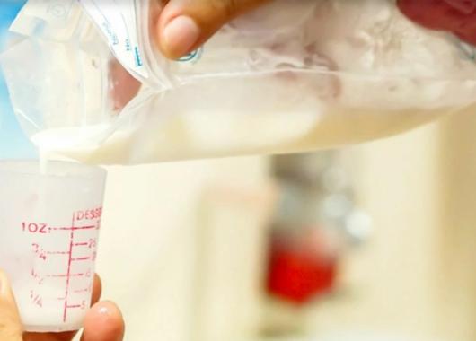 Photo of expressed breastmilk being poured from a storage bag into a container for feeding