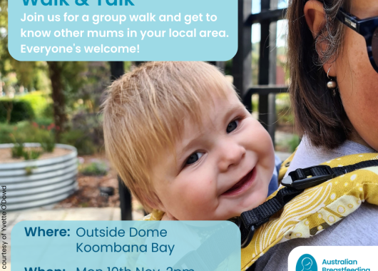 Happy baby looking towards camera while in a baby sling on the back of a mum's back