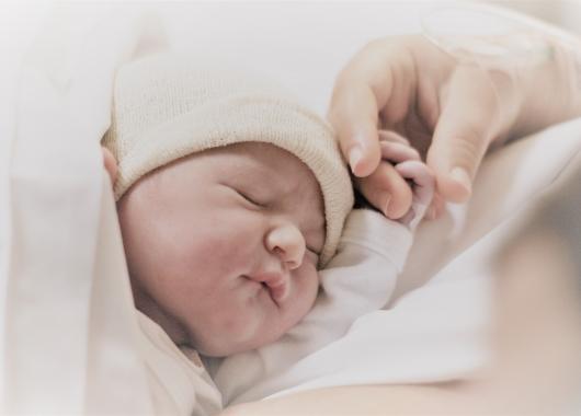 baby sleeping and holding parents fingers