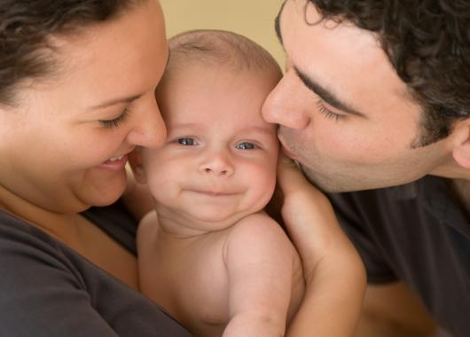 A woman and a man cuddle their baby