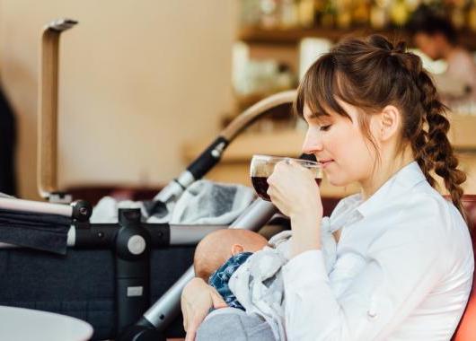 woman breastfeeding while drinking tea