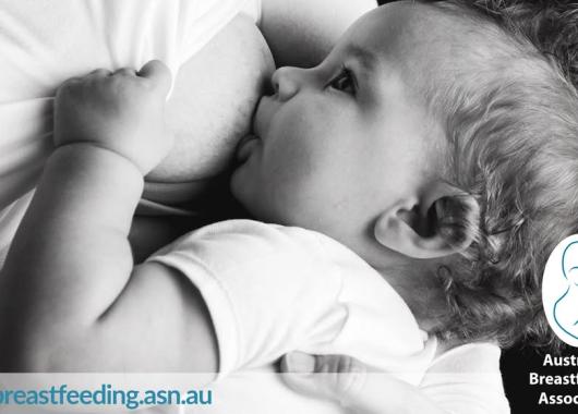 A baby breastfeeding and holding its mother's shirt