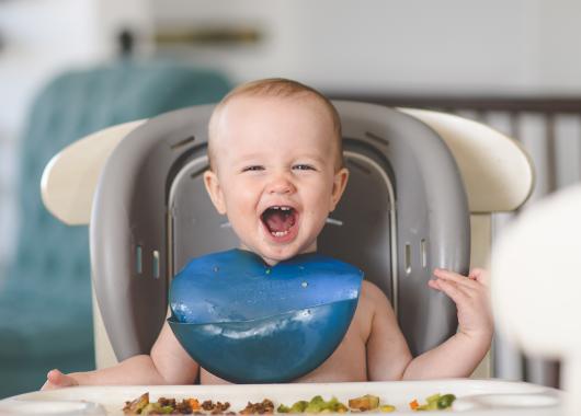 A baby sits in a high chair with a selection of solid foods