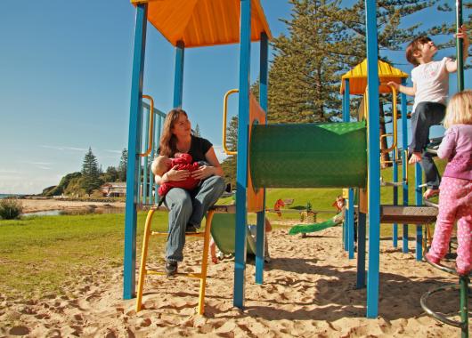 A women breastfeeding in the park while her older children play