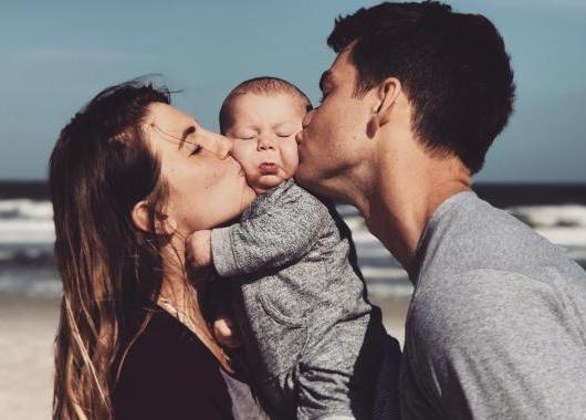 mother and father both kissing their baby