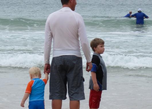 dad, toddler and big brother at the beach