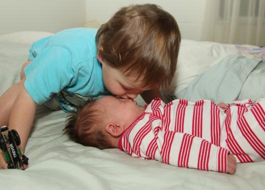 toddler kissing new baby