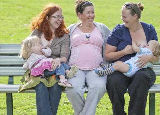 three women chatting and breastfeeding