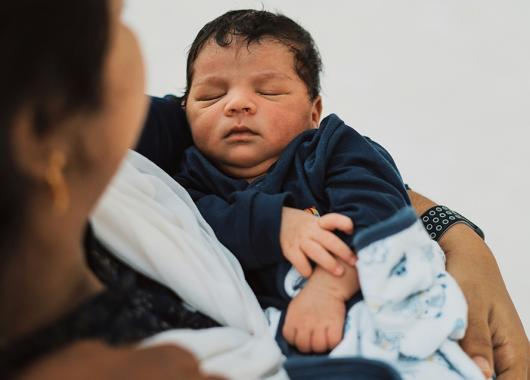A mother looks at the sleeping baby in her arms