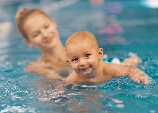 baby in swimming pool with mum holding them up from behind