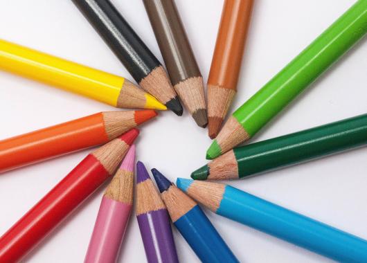 Rainbow colouring pencils in a spiral with their points pointing into the centre