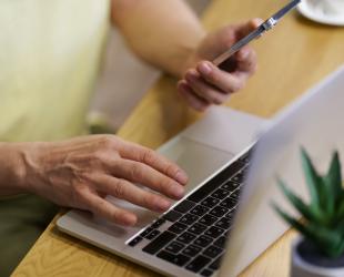 A close-up of a woman typing on a laptop.