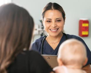 A health professional smiles at mum and baby