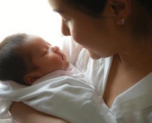 A woman holds her sleeping newborn baby