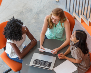 Three women sitting around table working