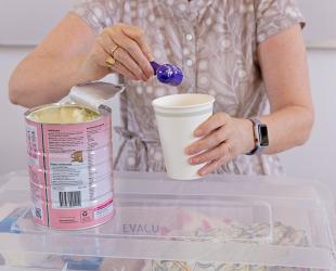 A woman prepares infant formula in a disposable cup during an emergency