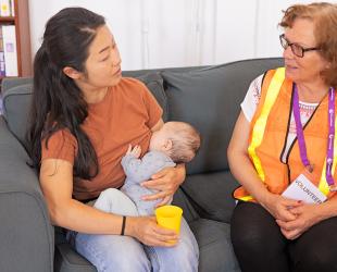 Woman breastfeeding young baby while talking to an emergency responder